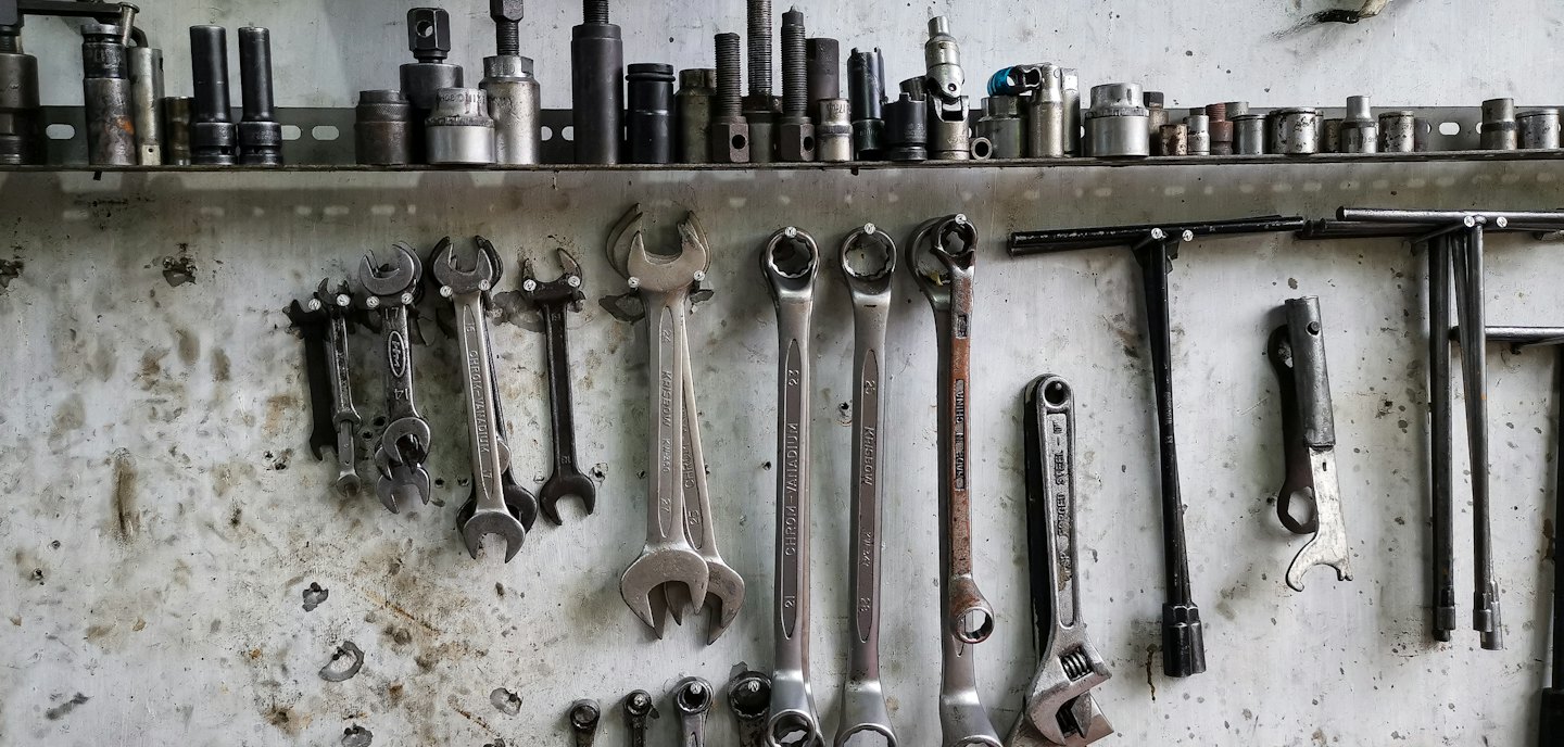 Metal wrenches and sockets neatly arranged on a workshop wall.