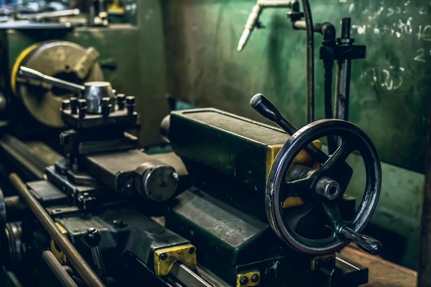 Industrial metal lathe machine with levers and gears in a workshop.